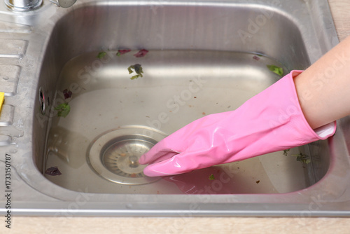 Papier peint Female hand in rubber glove cleaning clogged kitchen sink, closeup