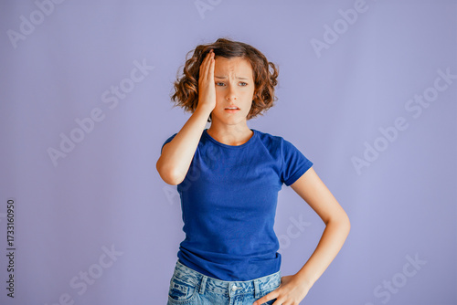 Anxious young student grasping head with troubled expression and stressed vibe for mental health concepts on vibrant blue studio background with emotional theme
