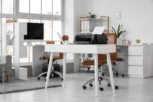 Modern printer on desk in o...