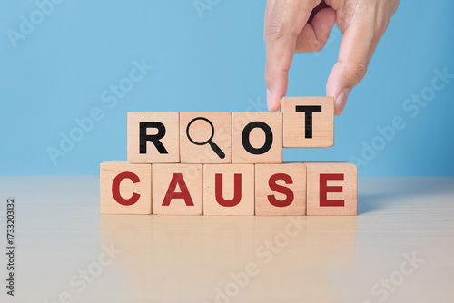 Root cause analysis concept. Define problems to find solution. Business problem solving. Hand holds the wooden cubes with text ROOT CAUSE and magnifying glass icon on grey background