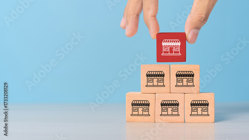 Obraz na płótnie Hand choose wooden block stack in pyramid with franchise business store icon for franchising to growth branch expansion and business banking loan