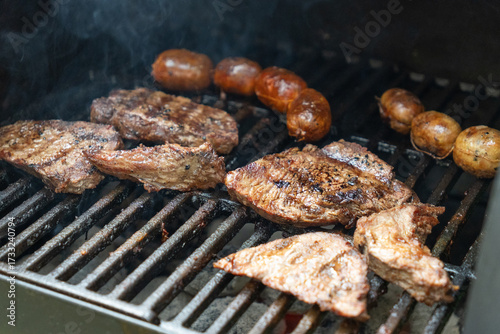 Photograph of homemade beef barbecue with chorizo ​​on an outdoor charcoal grill with smoke