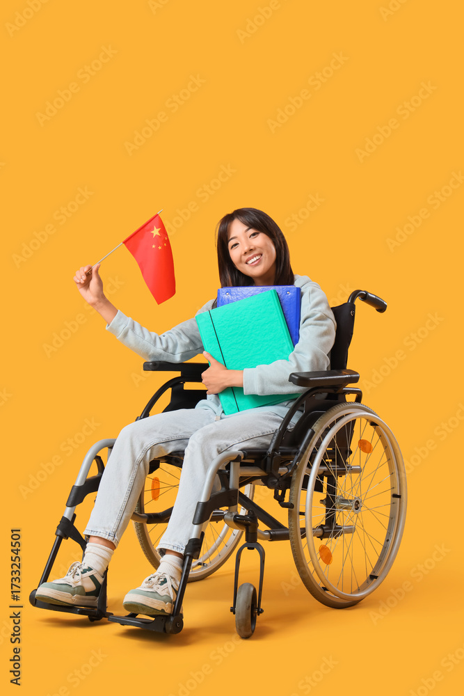 Obraz premium Young Asian woman in wheelchair with flag of China and folders on yellow background