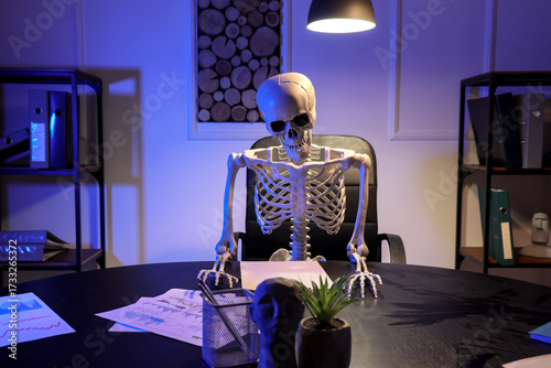 Human skeleton model sitting in office at night