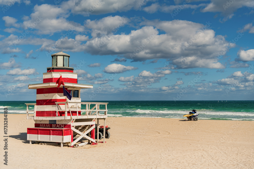 Fototapeta premium Lifeguard over Miami beach. Panoramic seascape of famous coastline. Summer in Miami Beach. Miami Beach jetty. Rescue tower against the blue sky in Miami. Beautiful coastal view of Florida.