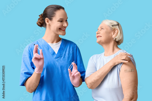 Smiling nurse holding syringe and vial with senior woman after vaccination, h...