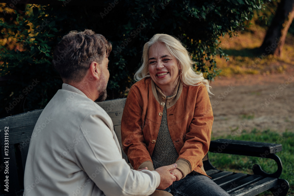 Fototapeta premium Happy senior couple holding hands and sharing a moment on park bench