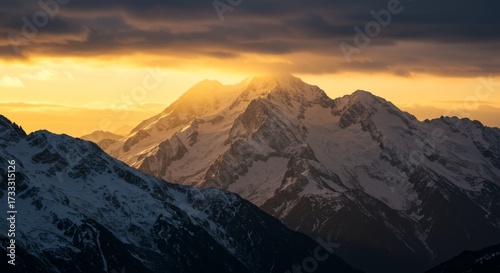 Snowcapped mountains at golden hour with sunburst effect