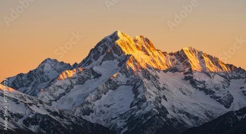 Snowy mountain peak illuminated by golden sunset light