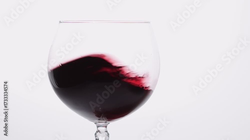 Swirling Red wine in a glass exudes sophistication and opulence on white background, creating an elegant ambiance.
