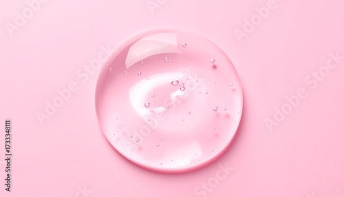 A transparent drop of pink cosmetic gel serum with bubbles on a smooth pastel pink background.