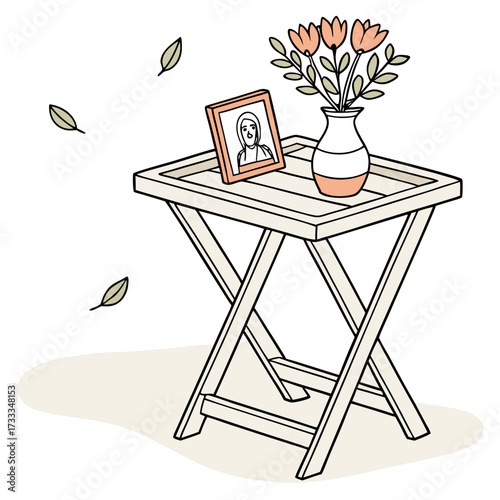 A simple illustrative drawing of a small folding table with a framed portrait and a vase of flowers with leaves falling around it