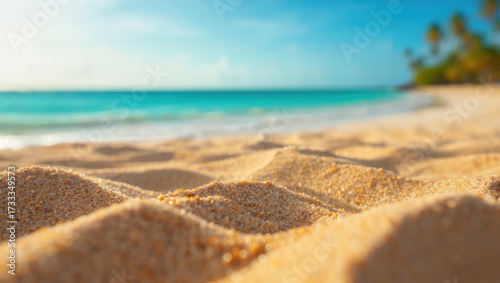 Closeup of sand on a tropical beach with turquoise water and palm trees in the background, creating a serene and inviting vacation scene