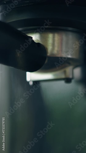 Barista hand rotate a portafilter holder into the group head coffee machine. Barista Hand Putting Portafilter in Coffee Machine. Close Up