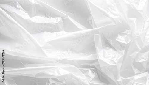 Close-up abstract view of a crumpled, white plastic sheet with folds and highlights