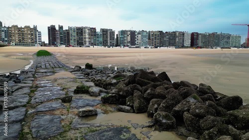 Coastline of Blankenberge in autumn, pier with rocks and high-rise apartments on boardwalk