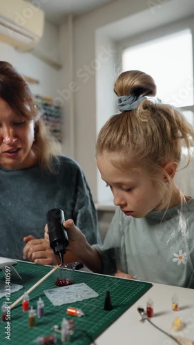 Mother teaching daughter handmade resin art, family craft project with epoxy accessories and home workshop, developing child creativity and skills