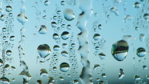 Raindrops clinging to glass ethereal blue background
