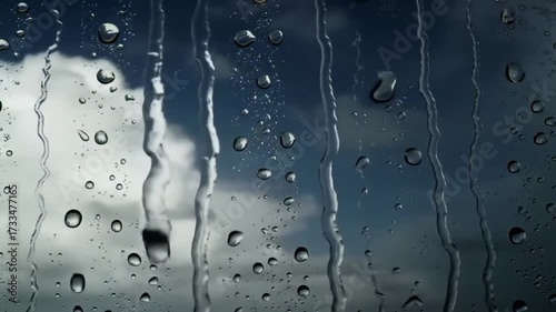 Raindrops cascade down glass on cloudy day