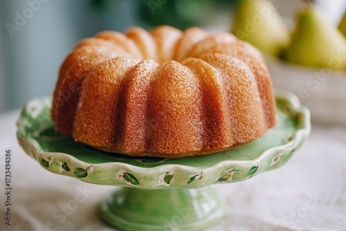Bundt cake on green ceramic stand with hand painted pear design in soft morning light
