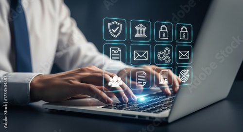 Businessman working on laptop with oversized holographic AML compliance and finance icons (shield, bank, lock, tax, envelope, gears, team, document, target) — fintech regulation and cybersecurity conc