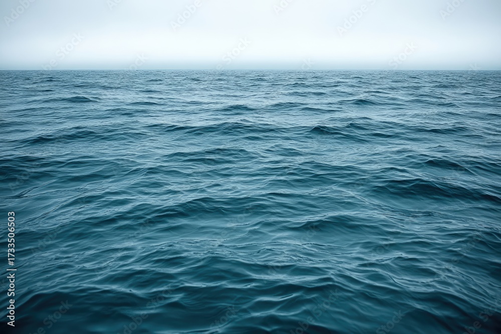 Fototapeta premium Rippled blue sea under a hazy, overcast sky.