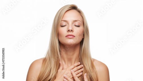 A serene woman with closed eyes, radiating tranquility, gently touches her chest with both hands in a studio shot, portraying a sense of calm.