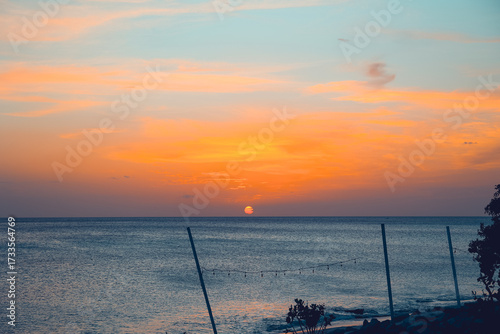 Floating in the waves at sunset, sun just above horizon, going down, orange sky, tranquil sea. Peaceful moment, vacations, summer mood. Dominican Republic. Horizontal video.