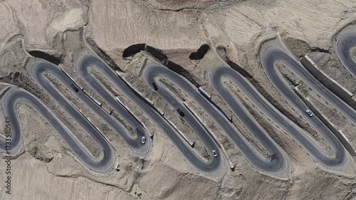 Aerial view of the winding Panlong Ancient Road cutting through the rugged terrain, a ribbon of asphalt against the barren landscape, Panlong Ancient Road, China.