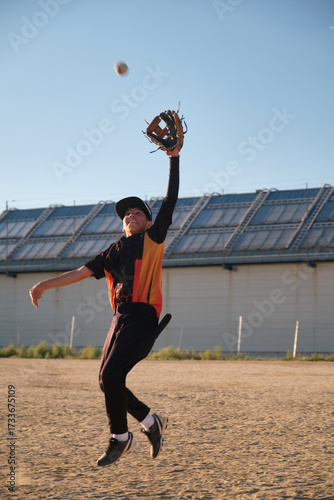 Photography Young baseball player jumping high with glove catching flying ball during game