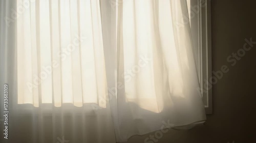 Sheer white curtains flowing in sunlight by the window indoors  