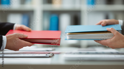 Business deal visual showing two people exchanging folders across a desk. Represents document transfer, contract agreement, and formal business negotiation between partners