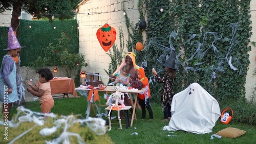 Little ghost scaring children at halloween backyard party