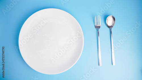 Empty Plate with Fork and Spoon on Blue Background
