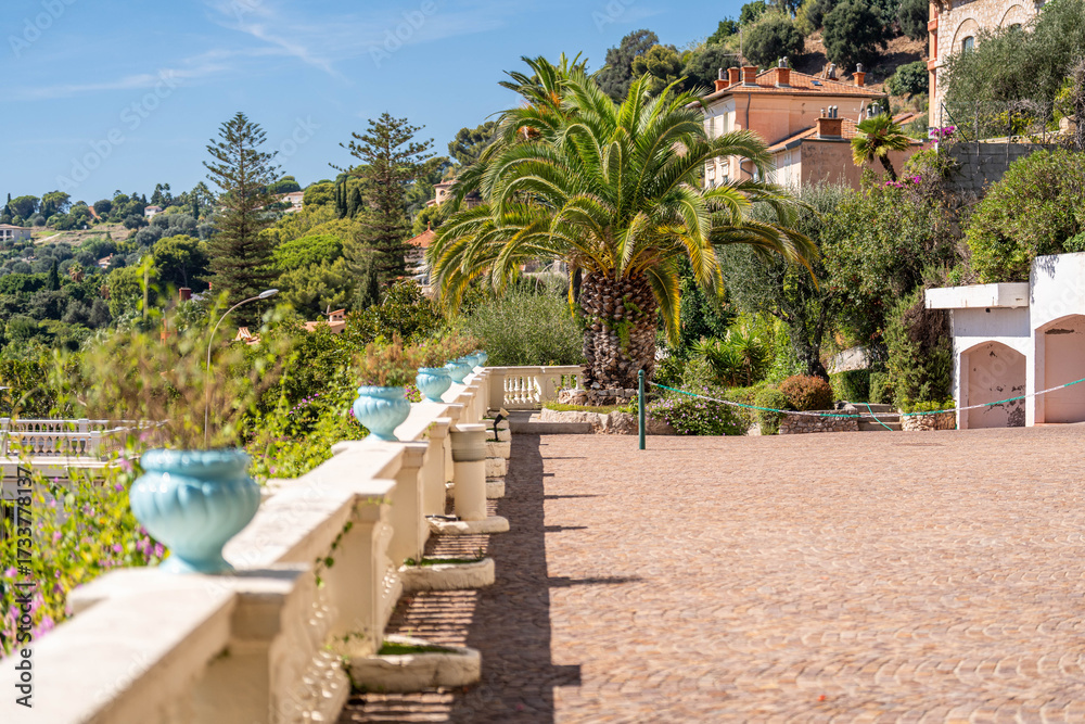 Fototapeta premium Terrasse méditerranéenne ensoleillée bordée de palmiers et de villas d’exception