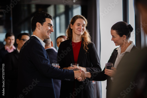 Professional man and woman greeting each other with a handshake during an offsite business meeting party, representing teamwork, leadership, and successful collaboration.