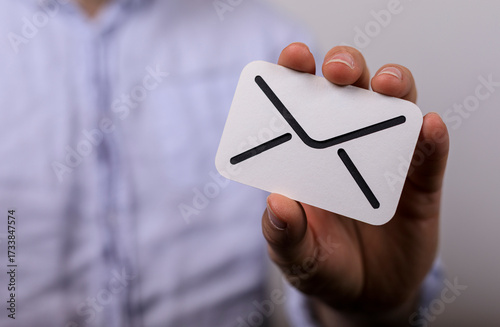 High-quality image of a hand holding an email icon card, perfect for websites and marketing materials. Represents communication, contact,