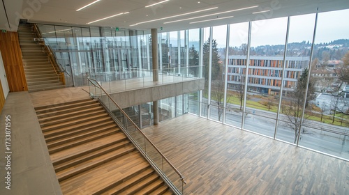 Bright atrium with stairs and large windows offering a view of surrounding buildings