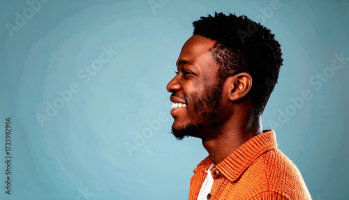 Profile view of a smiling Black man against a muted blue background