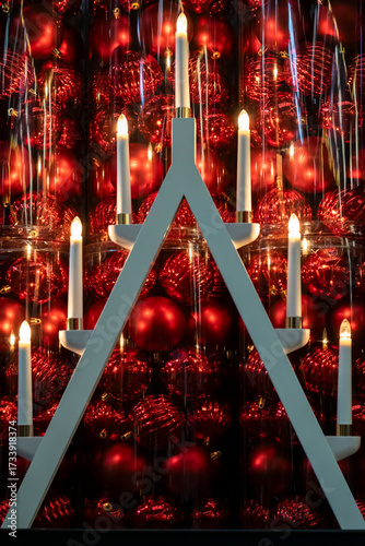 Christmas festive night background with advent candlestick and red Christmas tree balls sparkling in the dark, selective focus