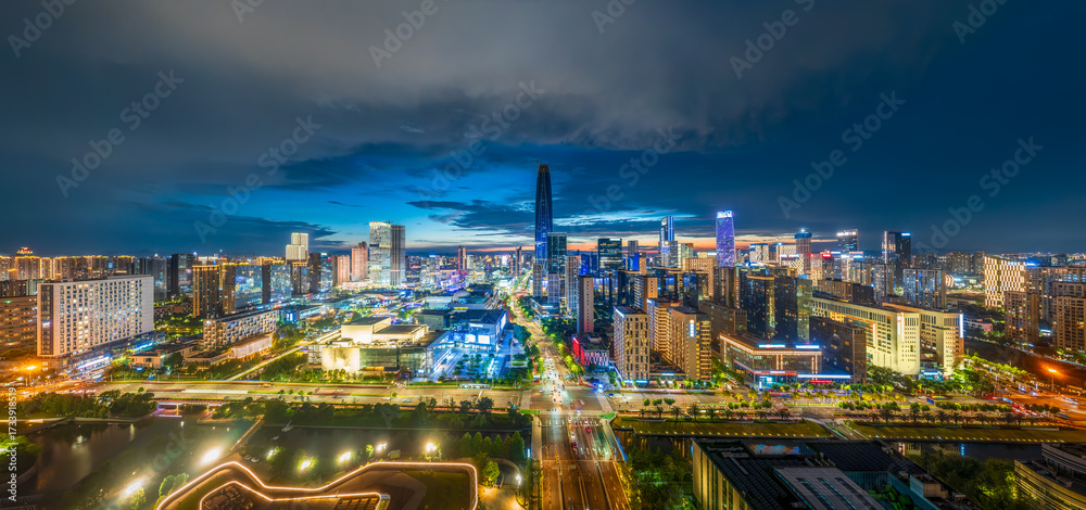 Obraz premium Aerial view of the modern city skyline with illuminated commercial buildings and busy traffic at night in Ningbo.