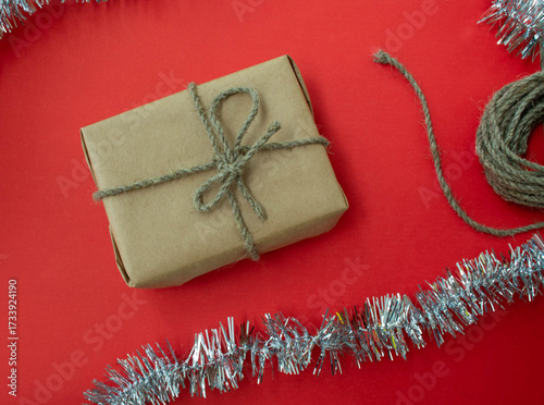 Packing Christmas gifts. Gift, twine and tinsel on a red background.