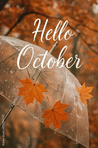 Hello October text. Transparent umbrella with raindrops and orange maple leaves clinging to its surface, set against a blurred autumn forest.