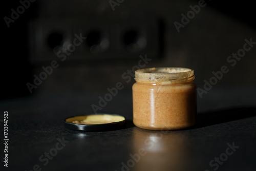 An open jar filled with jam. The lid is next to the jar. A blank background.