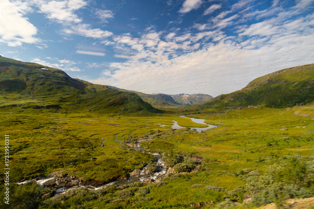 Fototapeta premium Amazing landscape of the Norwegian country during a perfect summer holiday with wonderful green fields, perfect cloudscape and breath-taking panoramic view as far as you can see with mountains and fjo
