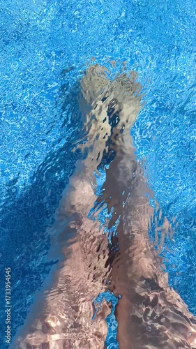 woman's legs under water in blue swimming pool