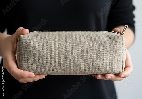 Hands presenting a beige canvas pencil case mockup for school or makeup accessories product shot on a plain background
