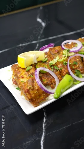 Delicious fried fish dish garnished with lemon onions and green chili peppers