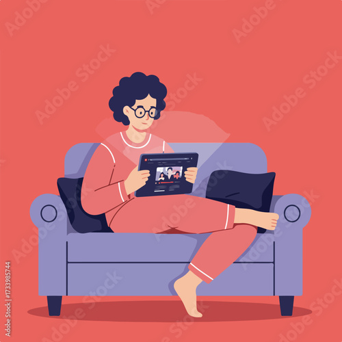 Person in pajamas watching videos on tablet while relaxing on a couch