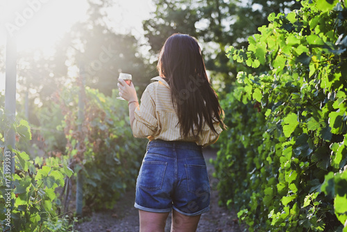 Young beautiful Smiling  italian woman walking at wineyard with a Glass of Red wine.Wine tourism at Tuscany,Italy